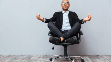 man meditating in office chair symbolizing company wellness program visually