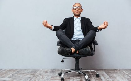 man meditating in office chair symbolizing company wellness program visually